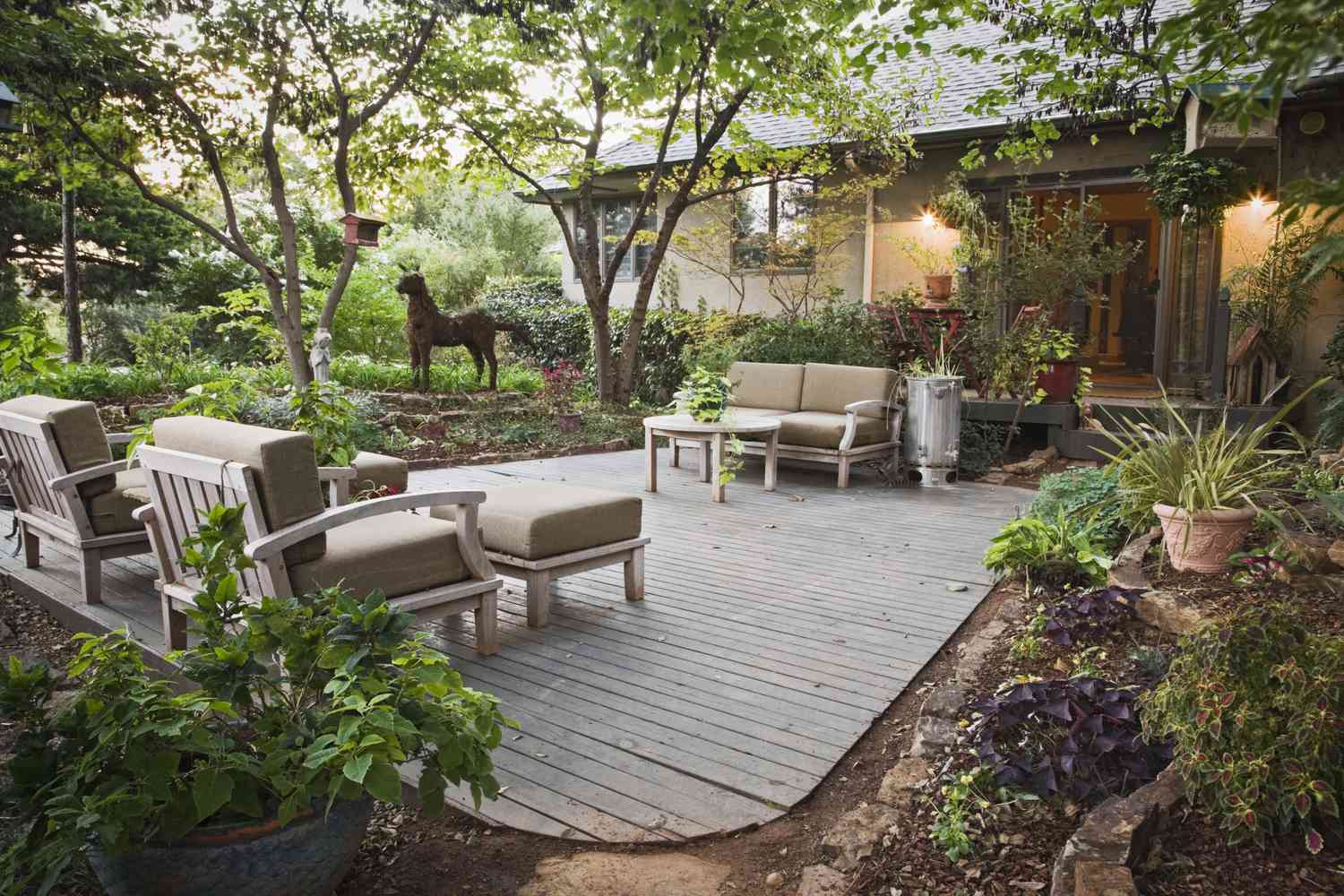 Cubierta con muebles en la parte trasera de una casa de un solo nivel y jardín