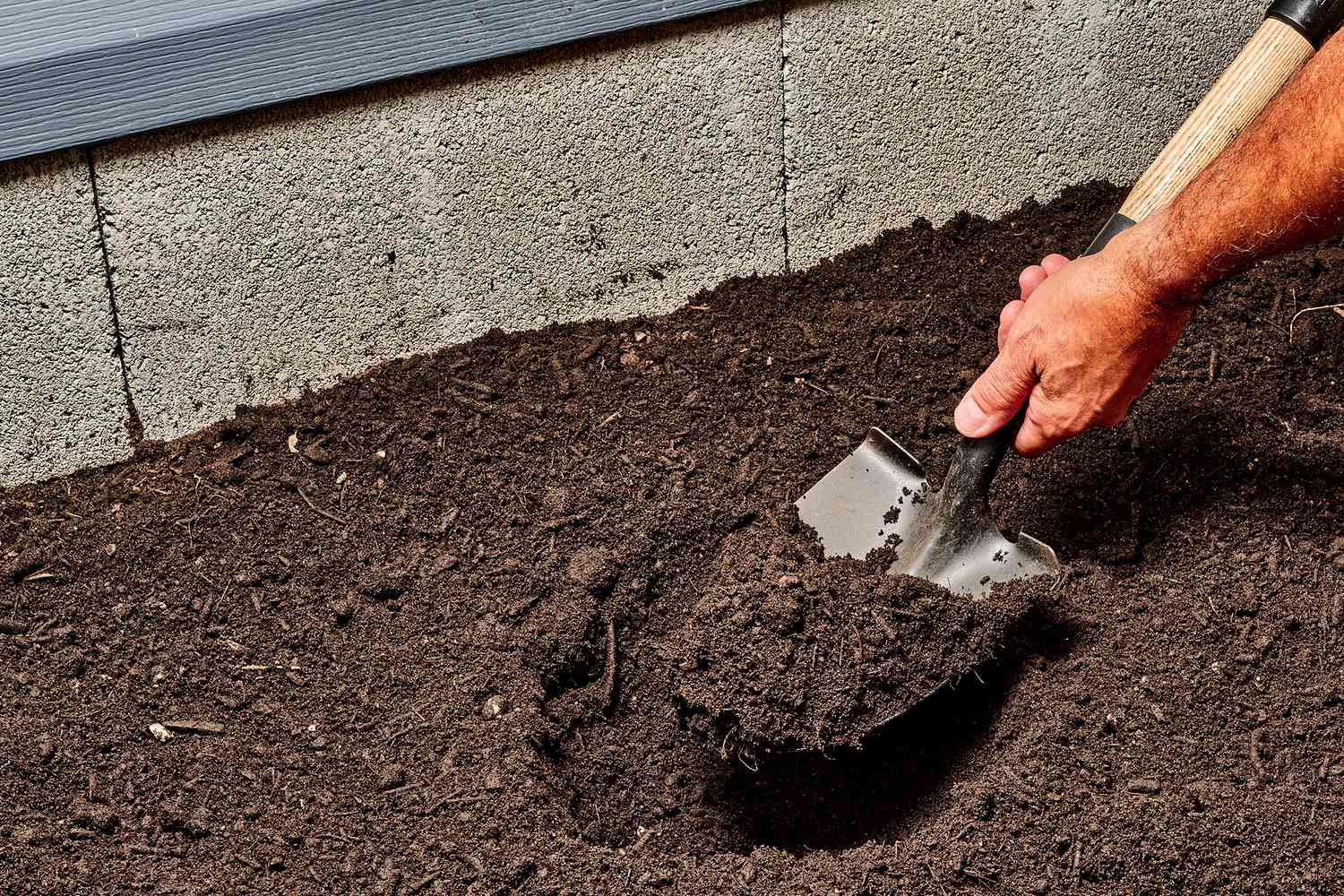 Schaufel gräbt Erde auf, um Bewässerungsrohre und Ventil freizulegen