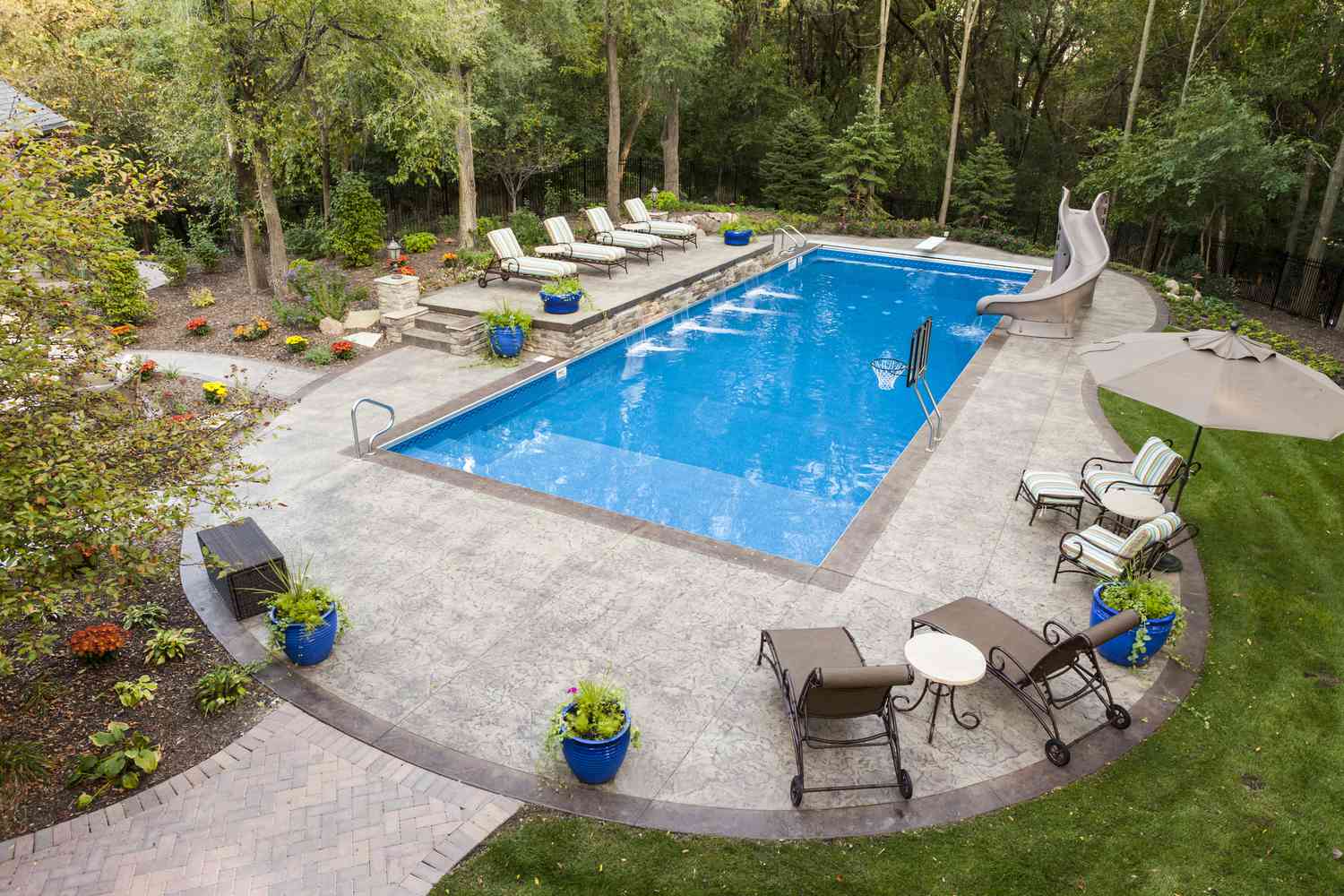Una piscina familiar con muebles de piscina rodeada de un patio.