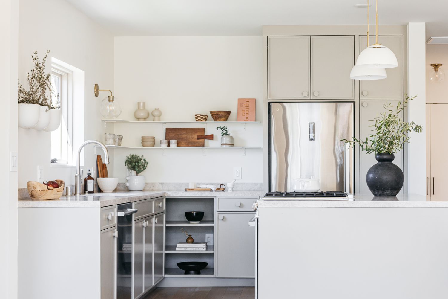 Cocina blanca con electrodomésticos de acero inoxidable y elementos de decoración neutros y plantas de interior