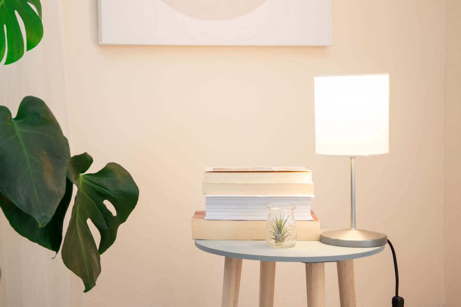 Pequena luminária de mesa emitindo luz ambiente branca ao lado de uma pilha de livros