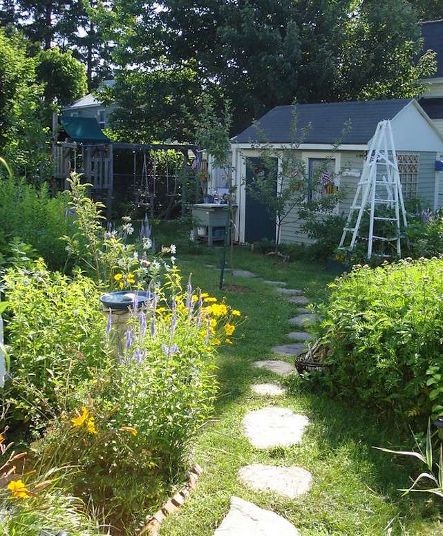 Camino de piedra en jardines de casas de campo con caseta de jardín