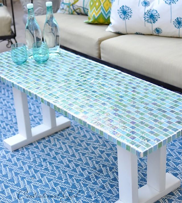 Une table basse extérieure recouverte de carreaux de verre bleus et verts