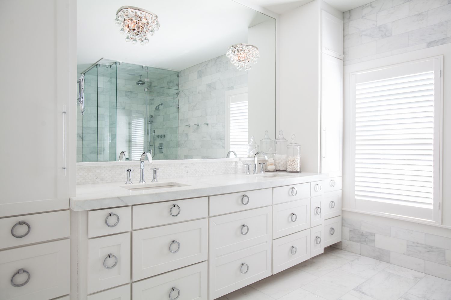 two crystal chandeliers in traditional marble bathroom