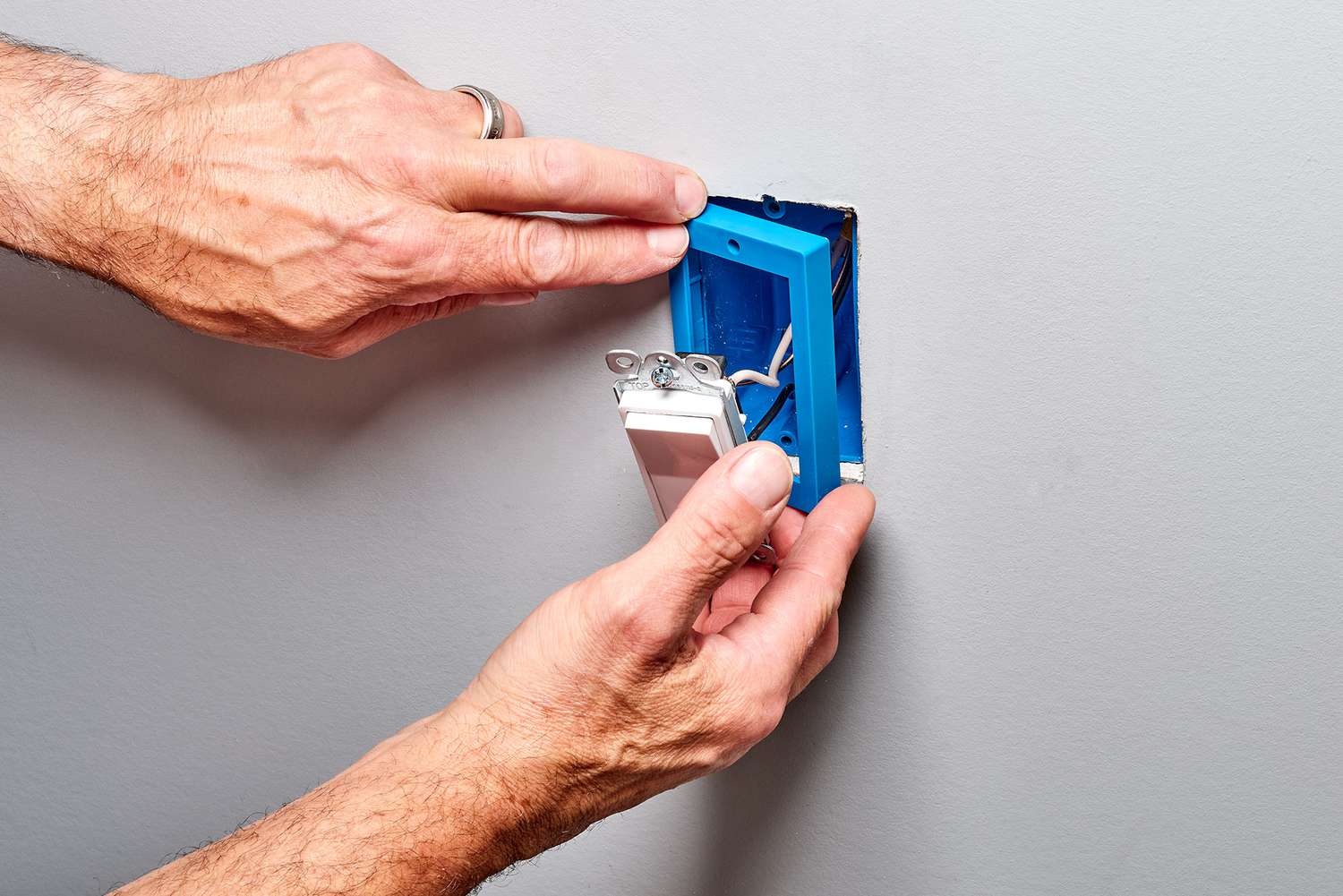 Blaue Dosenverlängerung wird über die elektrische Dose gestülpt, während der Schalter gehalten wird