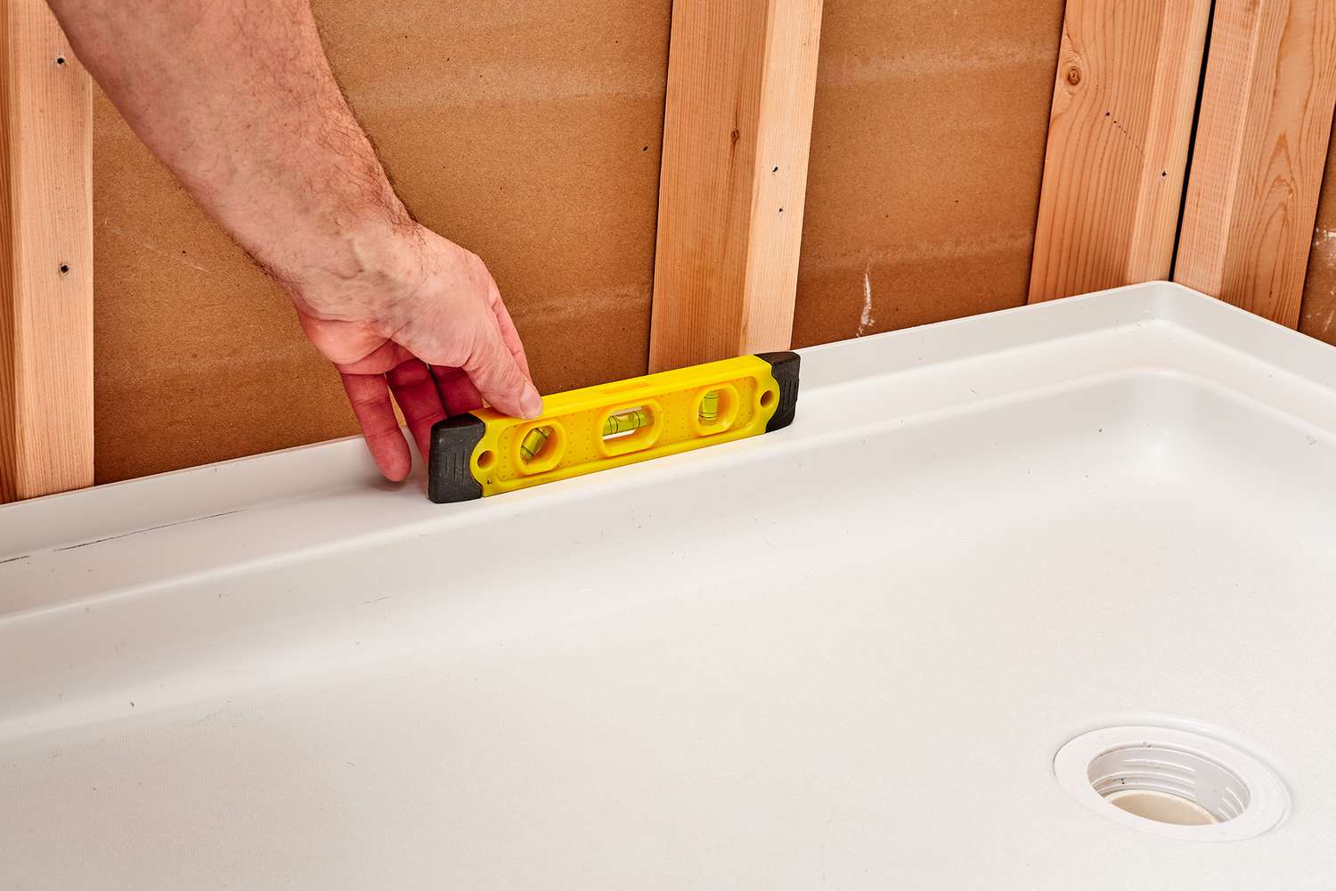 Yellow level placed on top of shower pan before anchoring