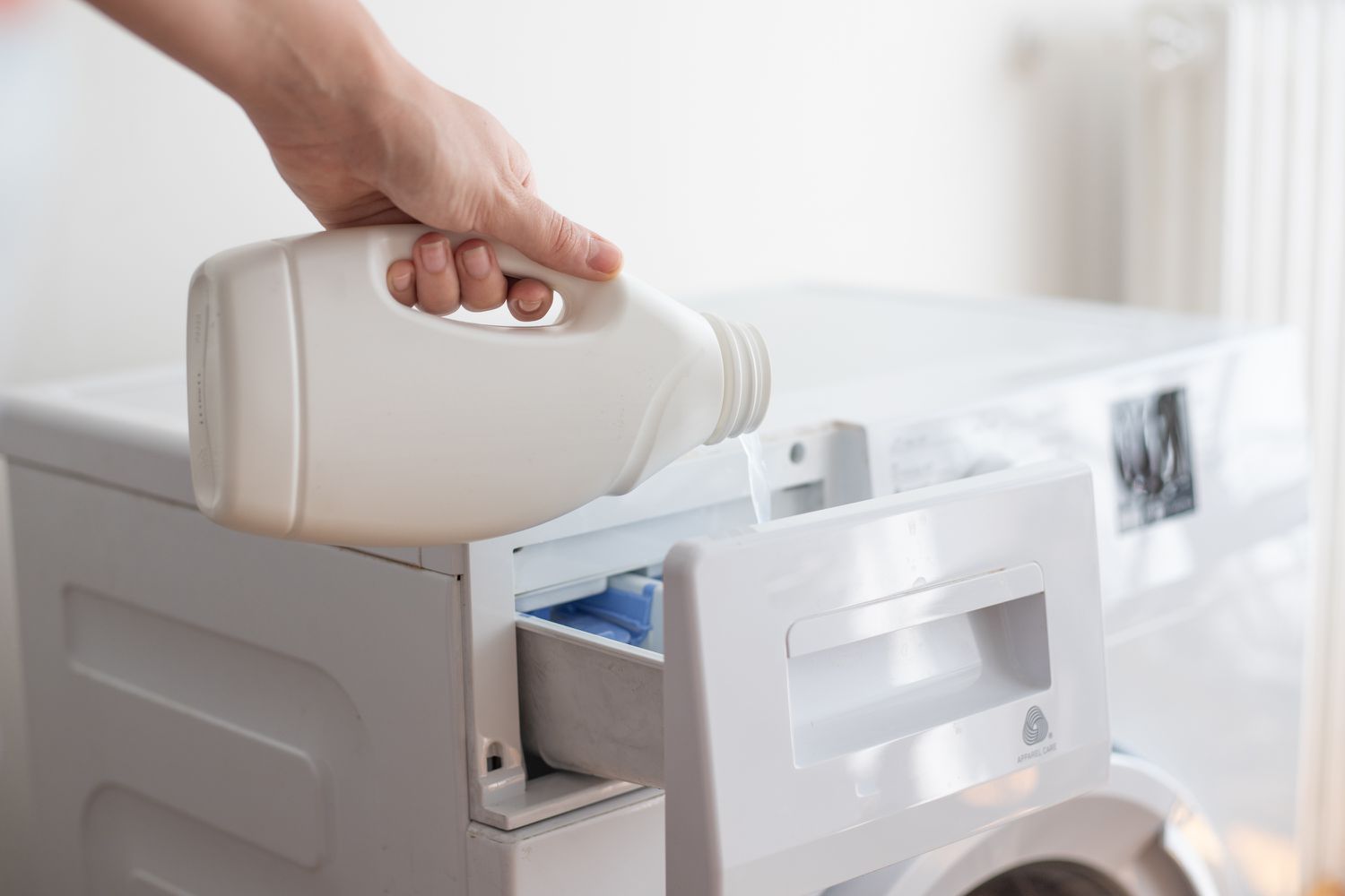 Blanqueador de cloro vertido en el dispensador de la lavadora para eliminar las manchas de tinte