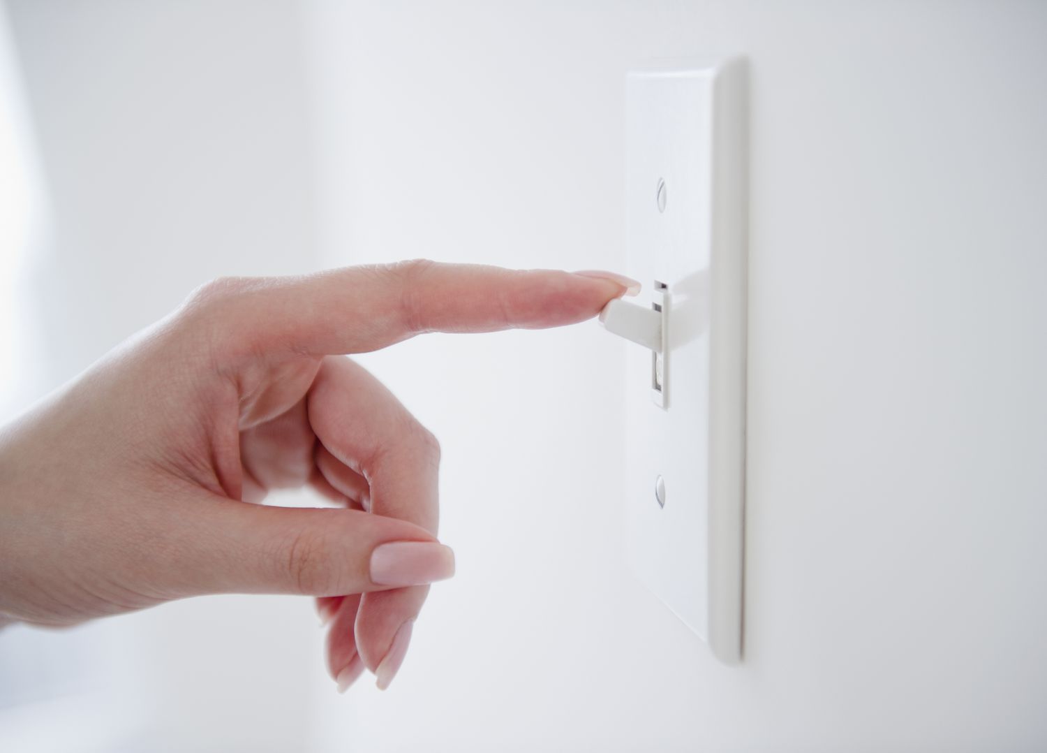 Mulher desligando um interruptor de luz branca.