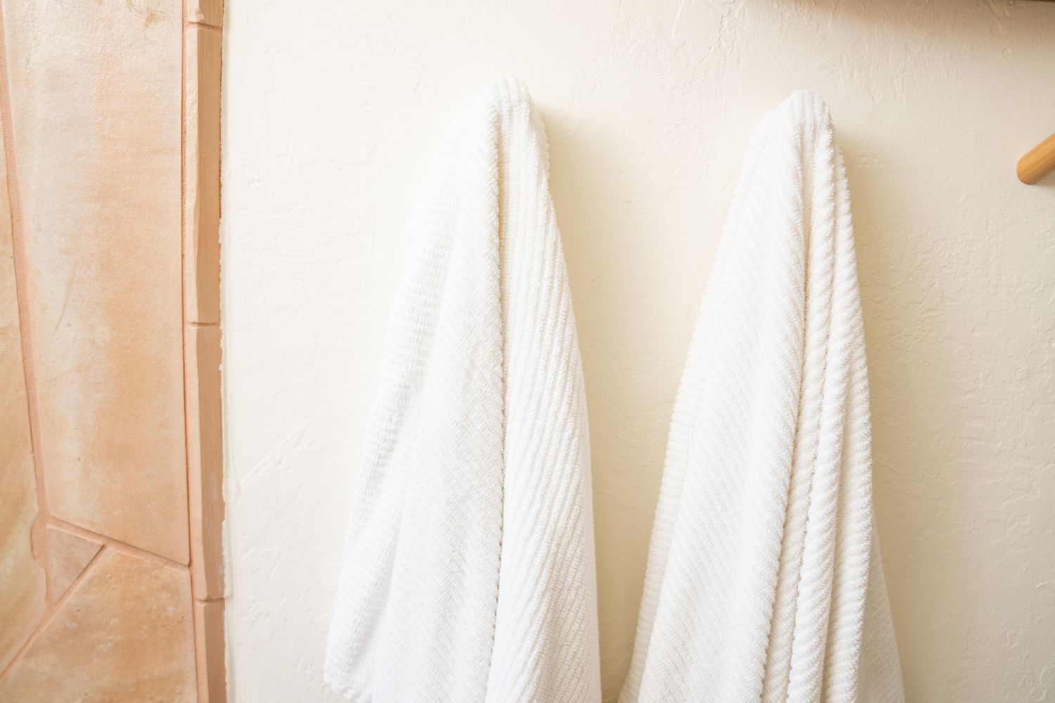 White damp towel hung up on wall stud in bathroom