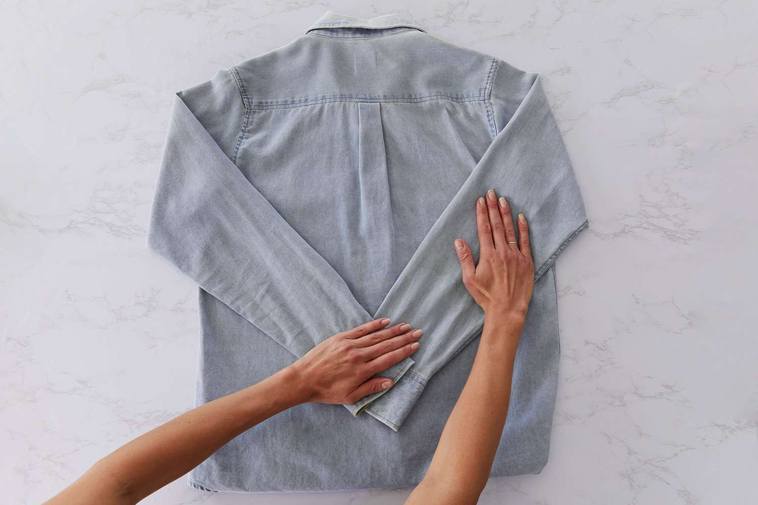 Mangas de camisa jeans cinza com botões dobradas para dentro em forma de V