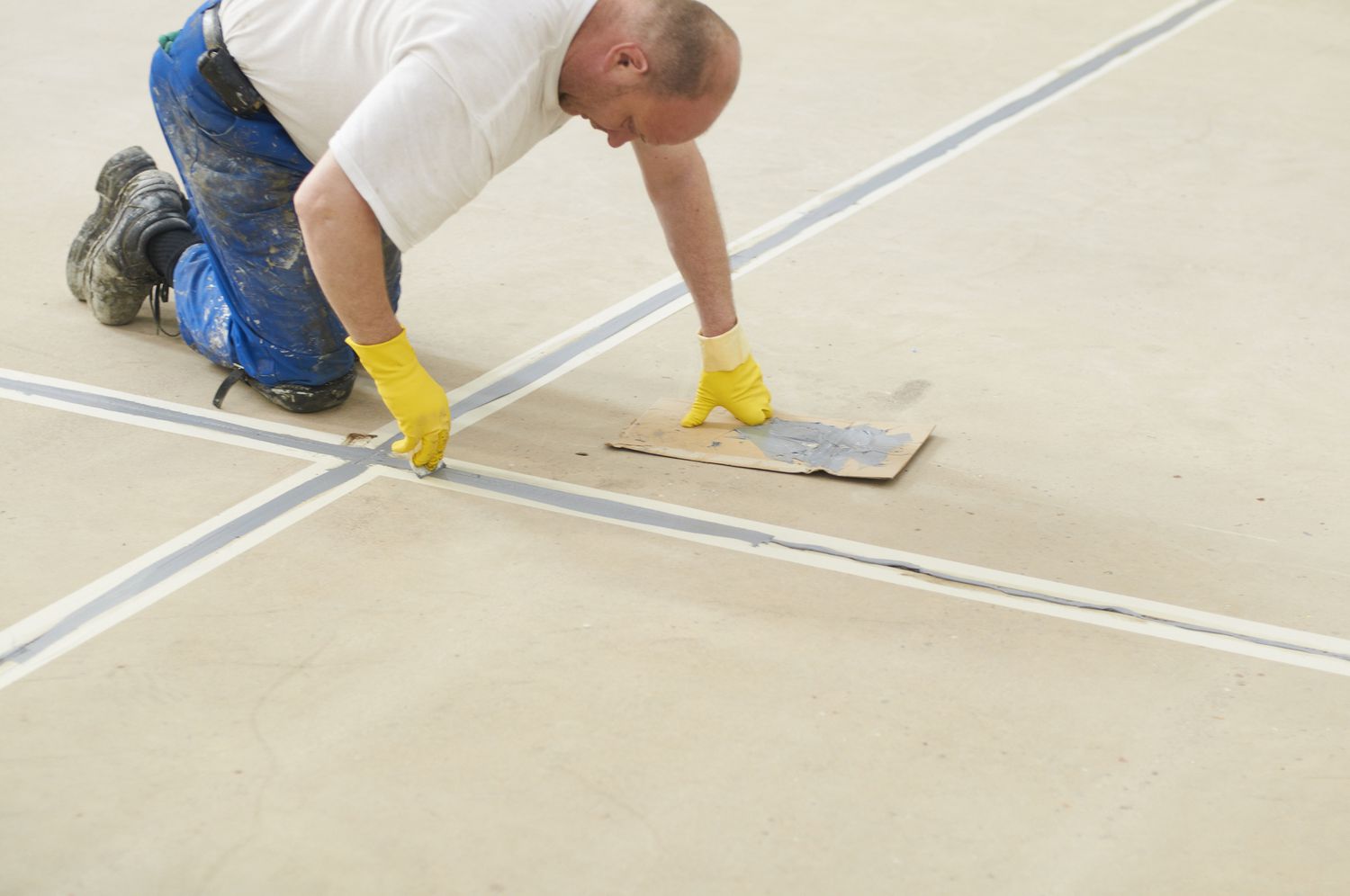 Arbeiter kniet und füllt Beton auf dem Boden ein.