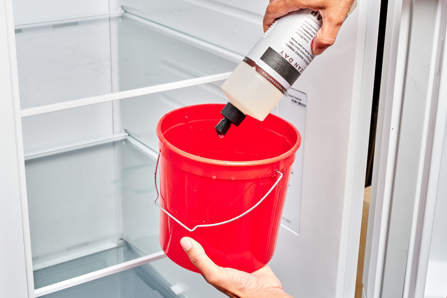 Jabón de fregar añadido al cubo rojo con agua tibia