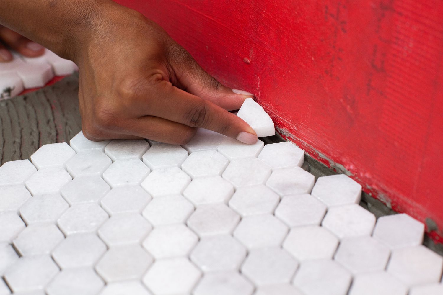 Baldosa de remate de mosaico blanco colocada en el borde del suelo de baldosas y la pared roja