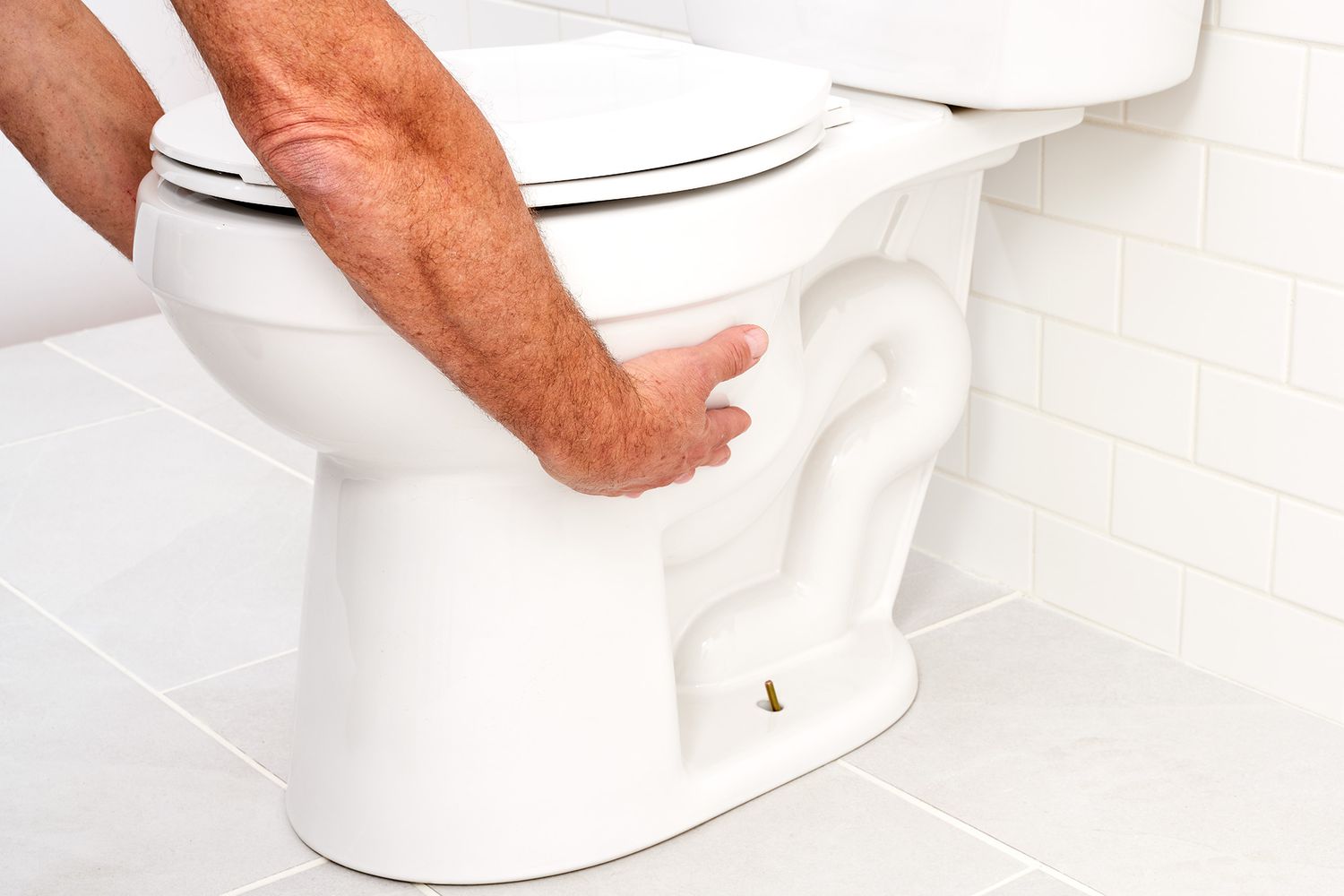 Weiße Toilette durch beidseitiges Anheben des Toilettenbeckens angehoben