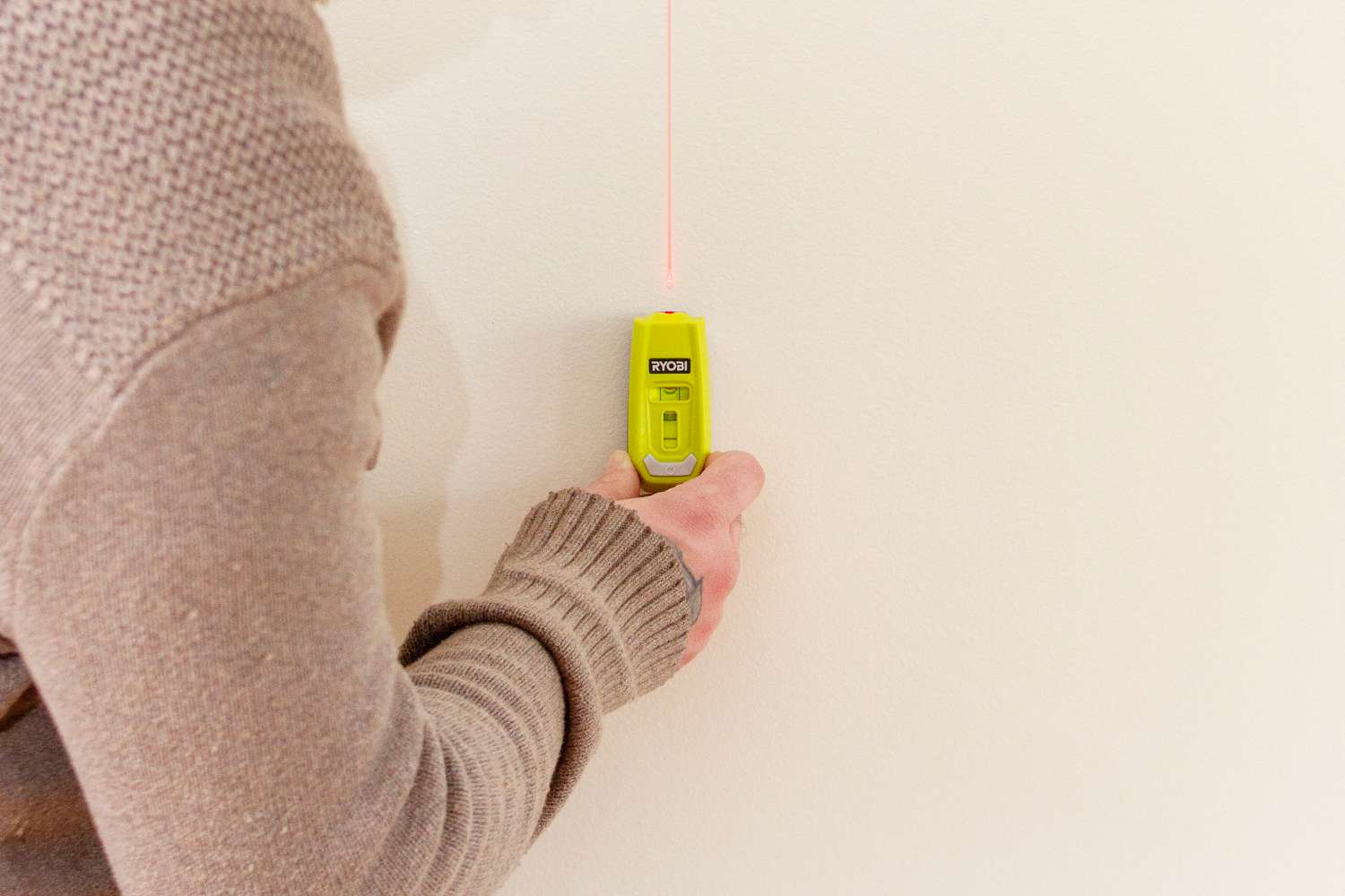 Medida a laser colocada na parede para marcar as diretrizes do papel de parede