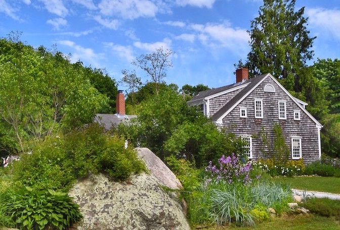 Gran canto rodado rodeado de flores frente a la casa de Cape Cod