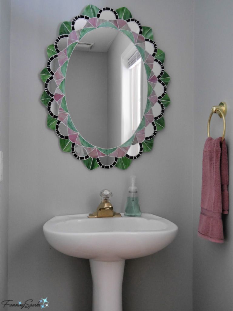 Un espejo de mosaico verde y morado sobre un lavabo