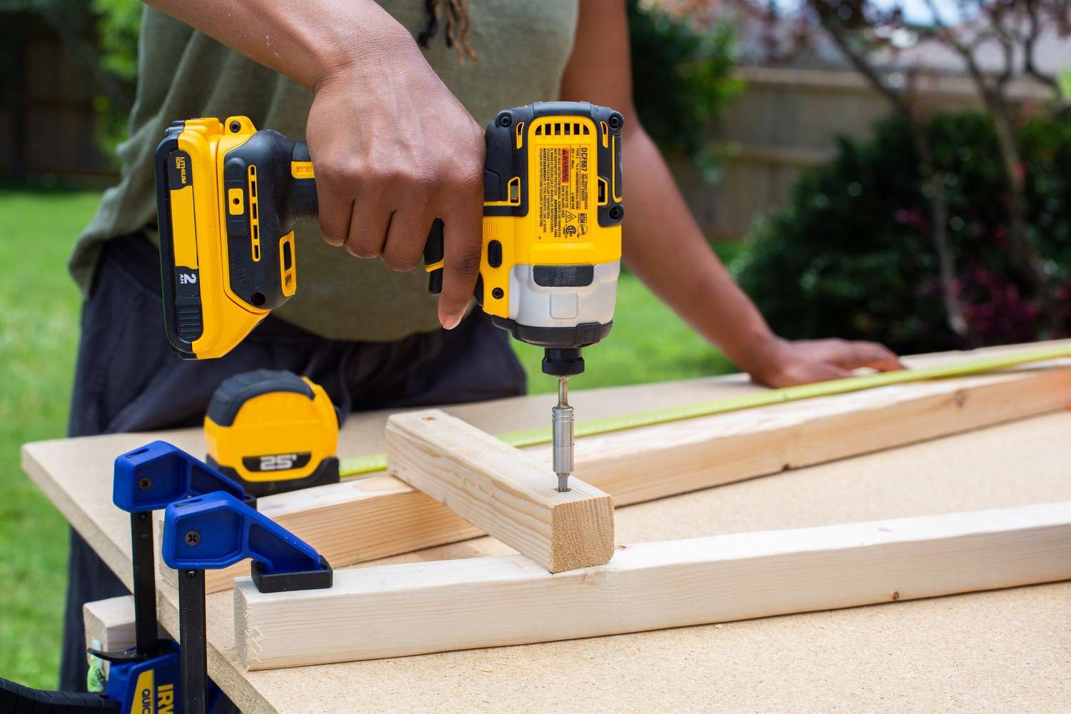 Die oberste Sprosse wird mit einer elektrischen Bohrmaschine an den auf dem Tisch befestigten Holzwinkeln befestigt