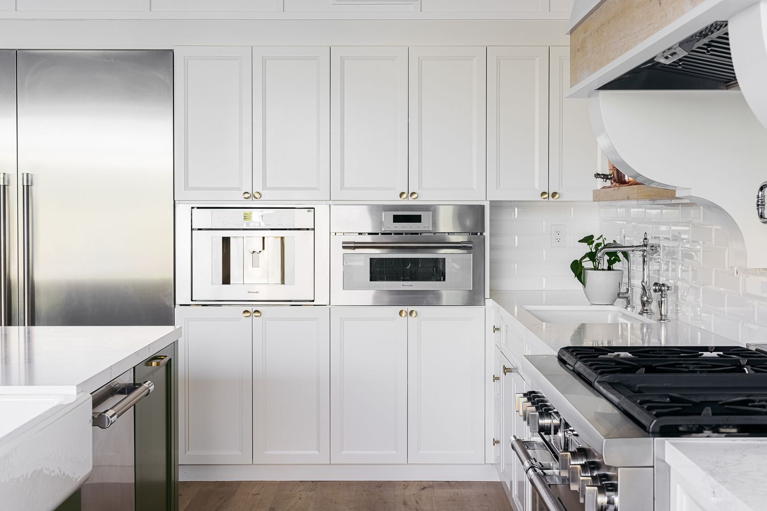 Armarios blancos en cocina abierta con electrodomésticos de acero inoxidable