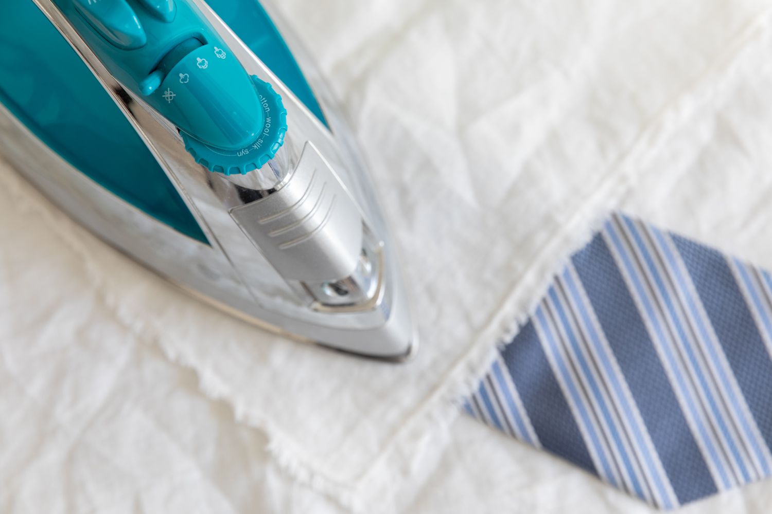 Corbata azul planchada con una plancha de vapor de color verde azulado y un paño entre medias