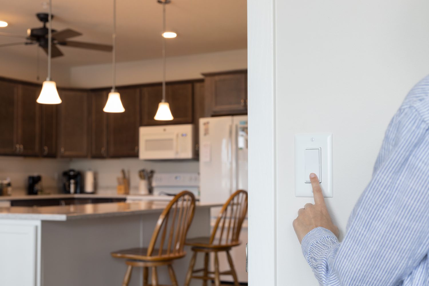 Interruptor de luz sendo pressionado para desligar as luzes da cozinha e diminuir a conta de luz