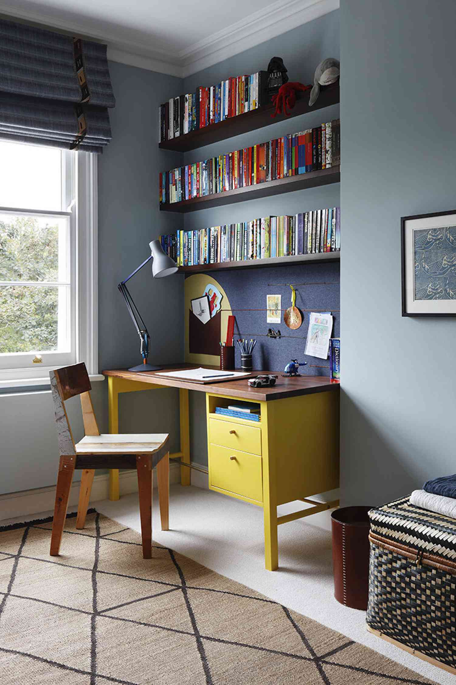 quarto com recanto de estudo, escrivaninha amarela com paredes azuis, estantes de livros