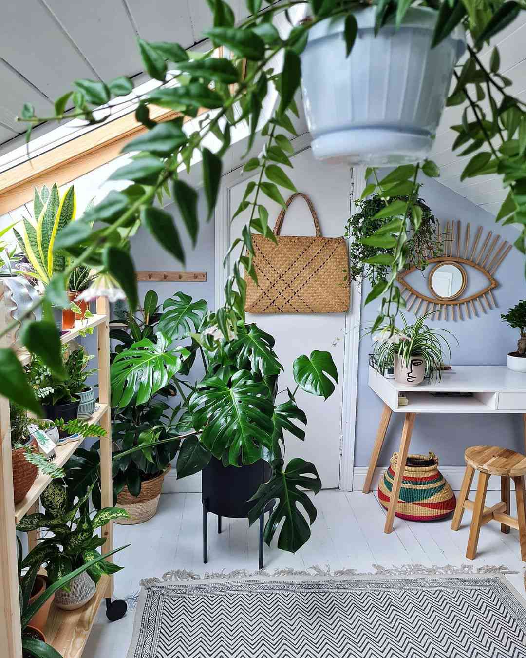 Sala com teto inclinado com escrivaninha e muitas plantas
