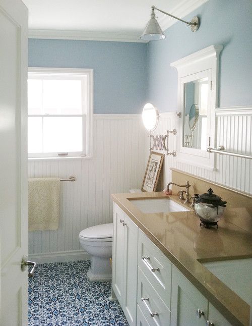 Ein Badezimmer mit Perlenplatten, hellblauer Wandfarbe und blauem Fliesenboden