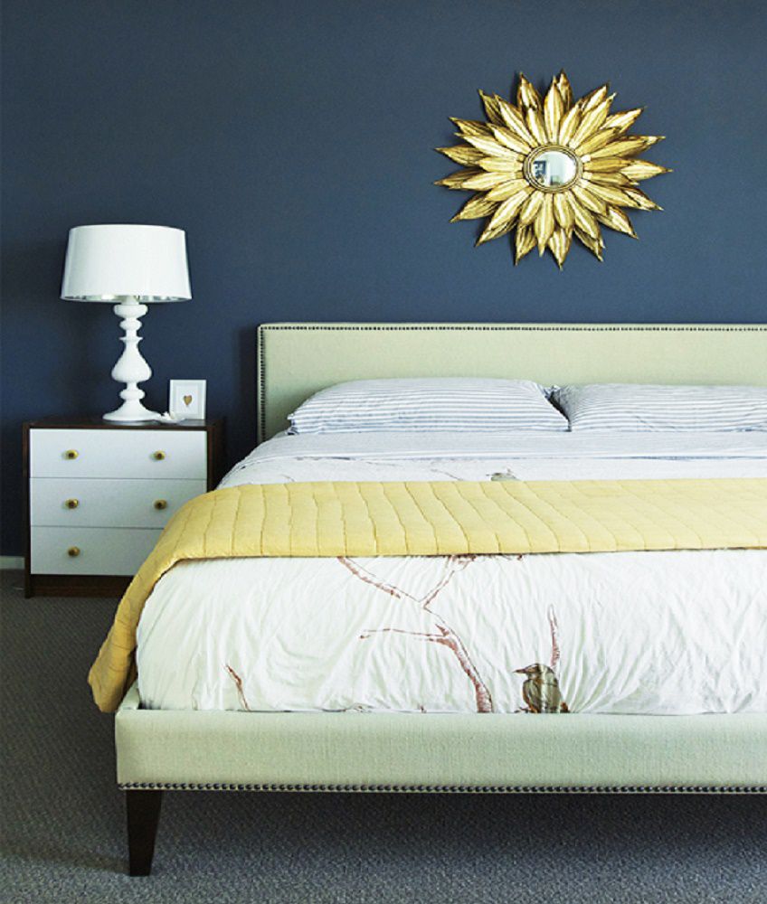 Chambre à coucher avec murs bleu foncé et miroir ensoleillé