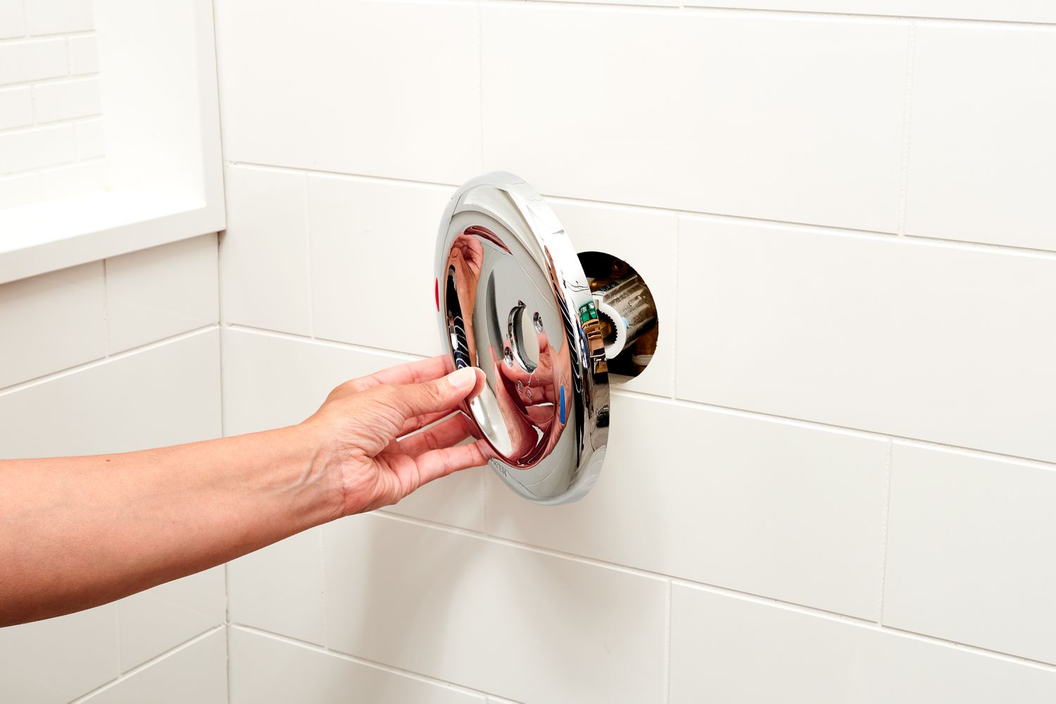 Shower handle trim plate removed from bathroom wall to expose valve