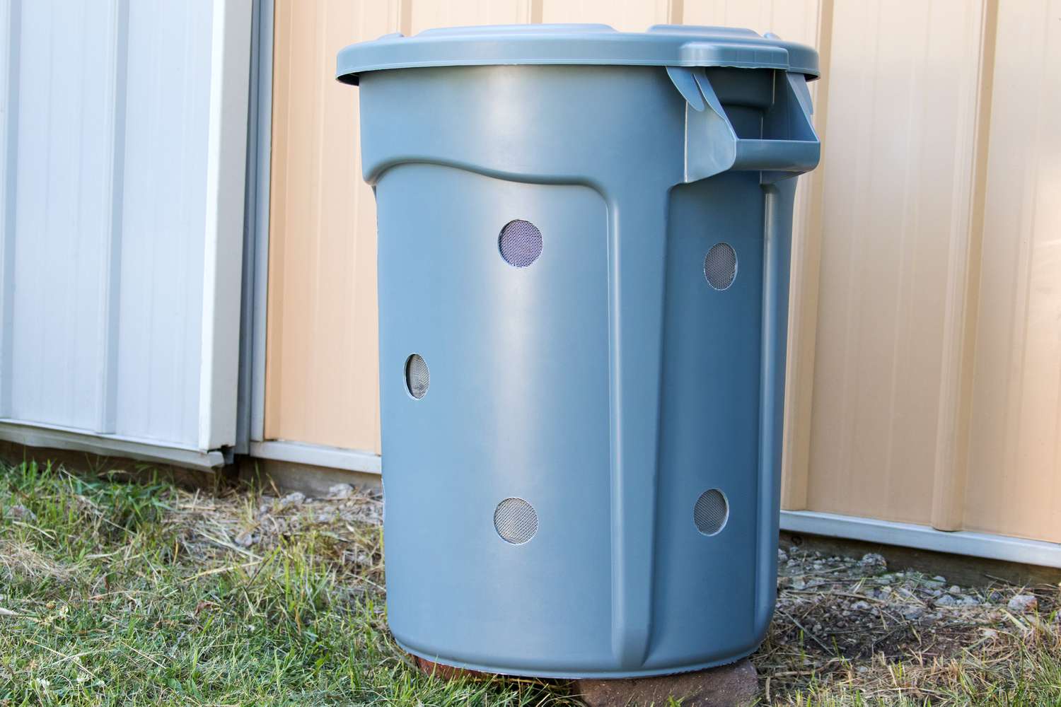Hellblauer Mülltonnenkomposter auf Ziegelsteinen im Hinterhof