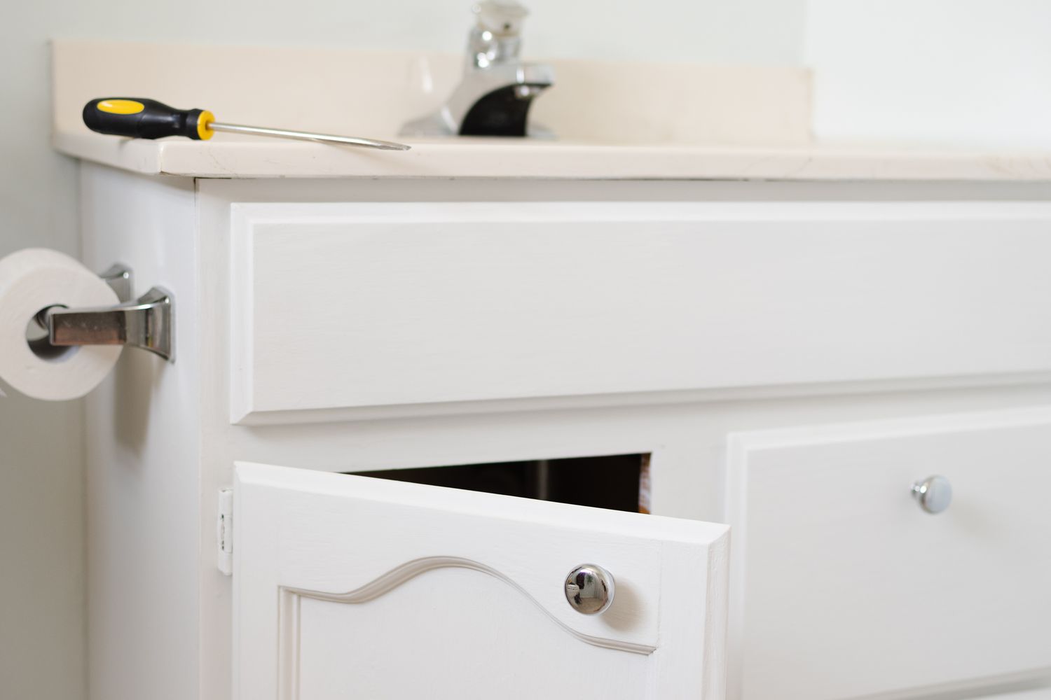 White bathroom cabinets reattached back in place in bathroom with screwdriver