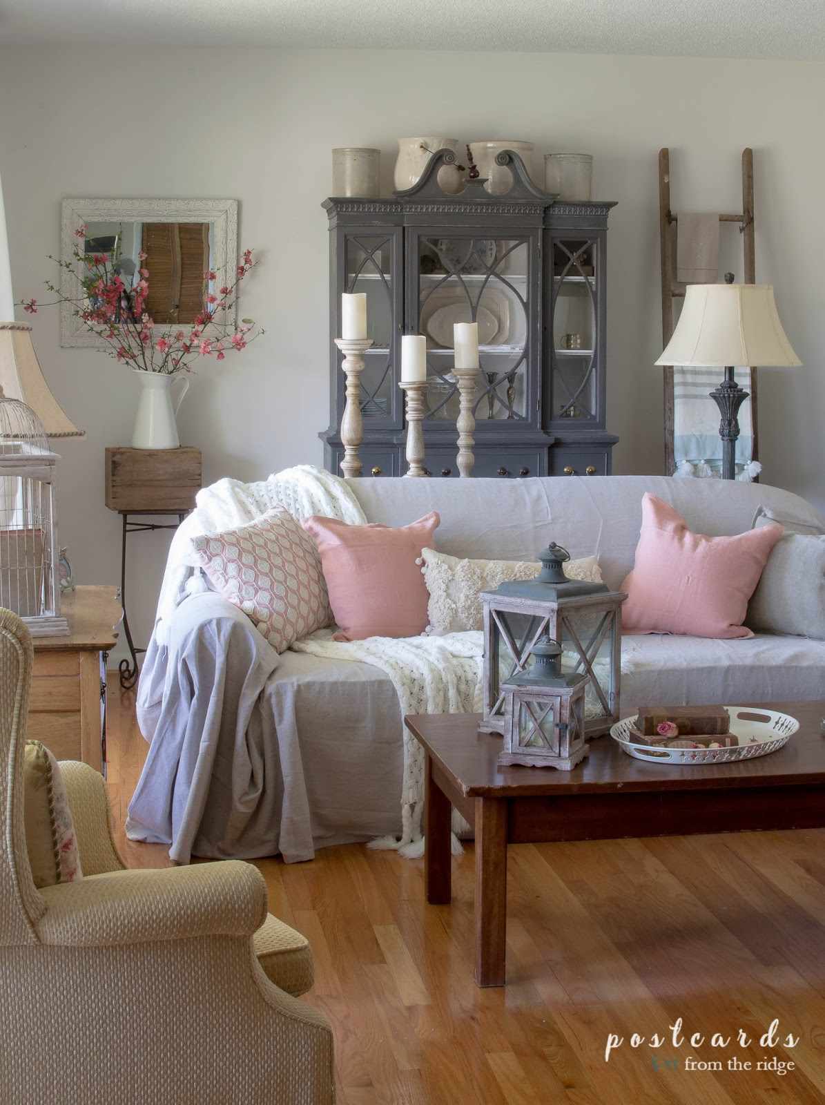 Ein graues Sofa mit Kissen darauf in einem Wohnzimmer mit viel Dekor.