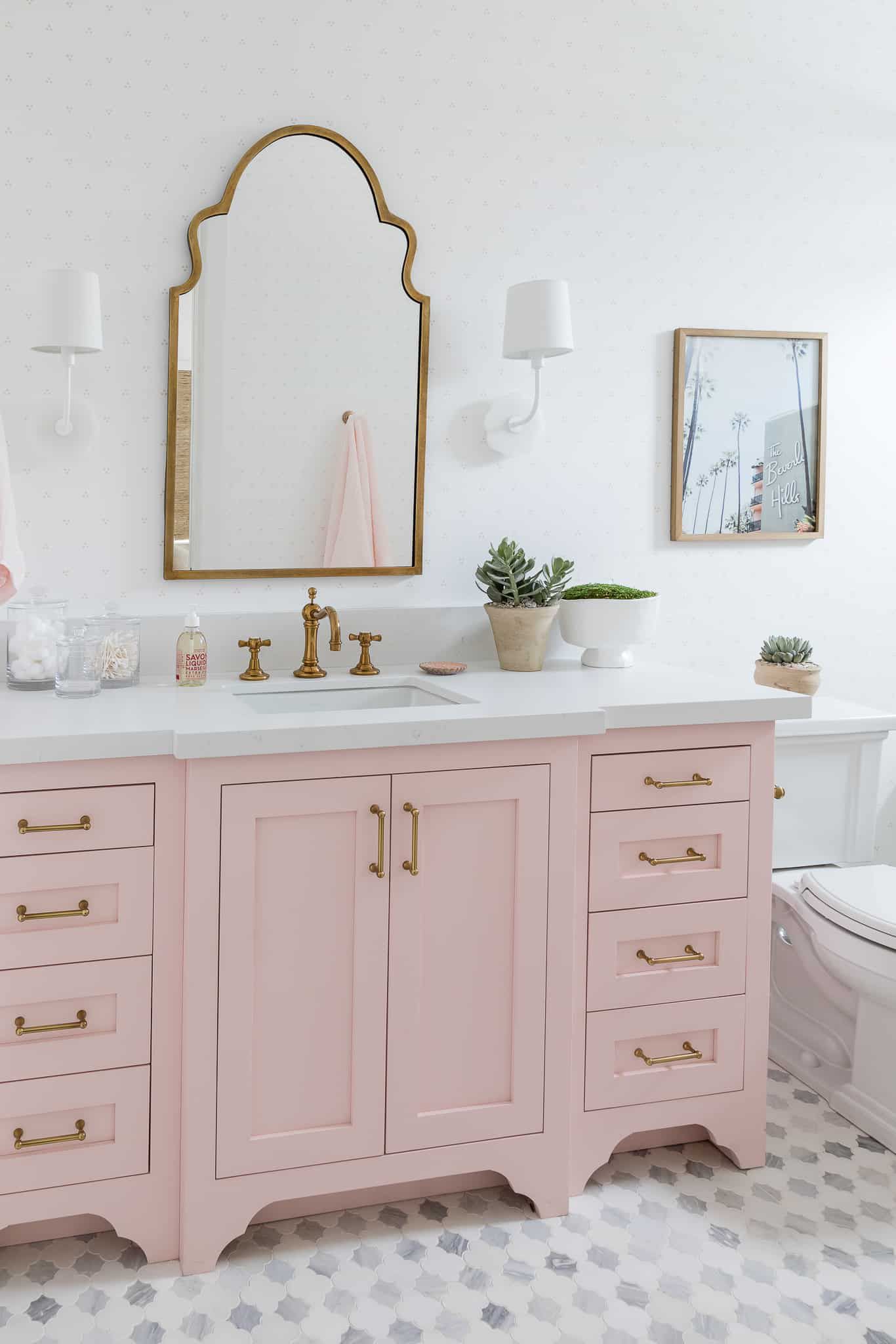 Um espelho ornamentado e uma penteadeira rosa no banheiro