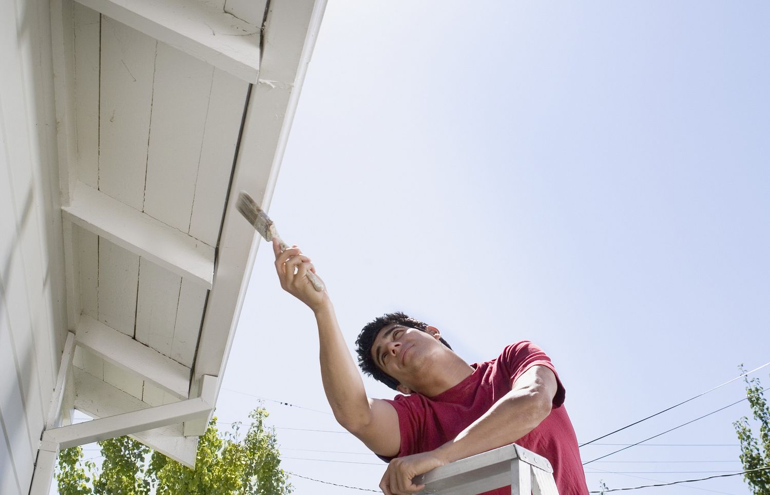 Un hombre pintando el alero de una casa