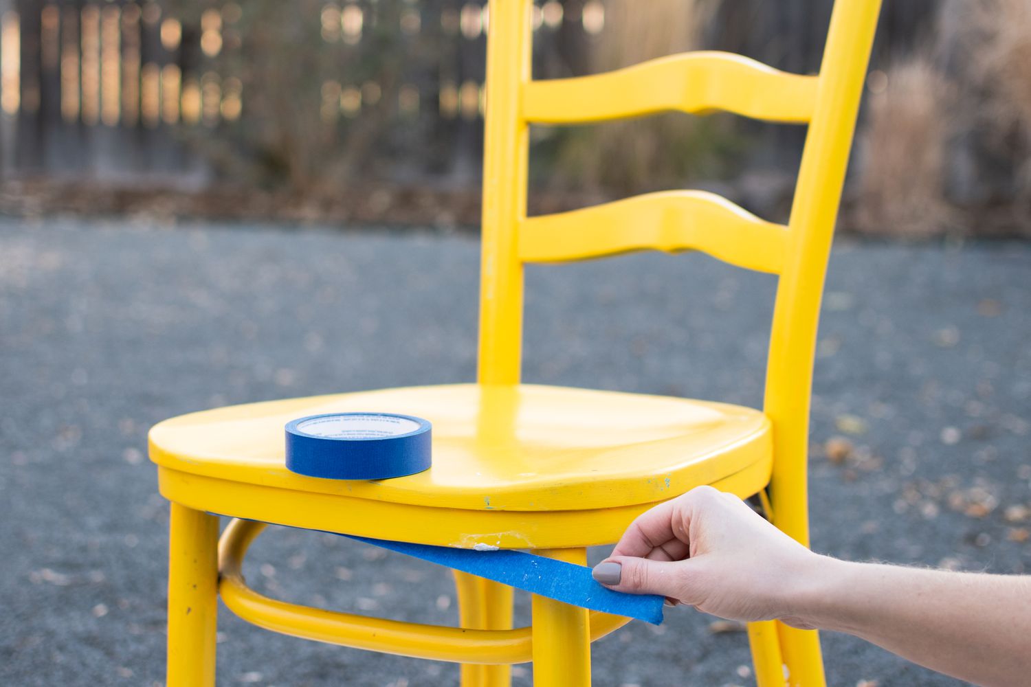 Blue painter's tape protecting areas on yellow chair for painting