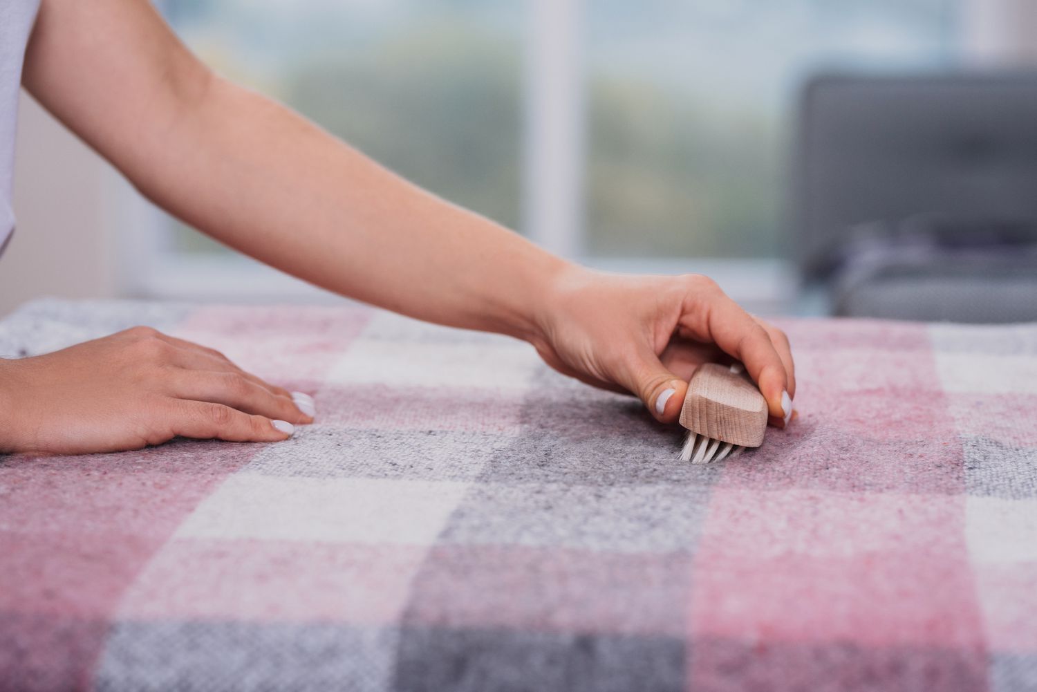 Bürste mit weichen Borsten streichelt rosa und graue Wolldecke