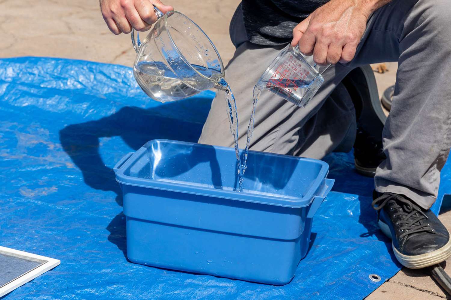 Haushaltsammoniak und Wasser in einen großen blauen Eimer gegossen