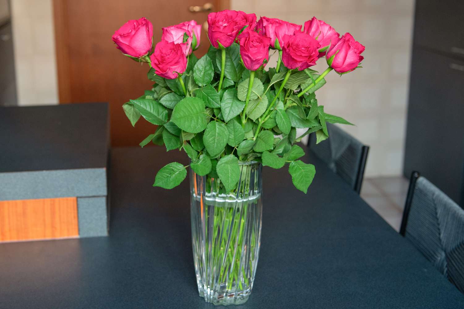 Hastes de rosas cor-de-rosa dispostas em vaso de vidro com água sobre a mesa