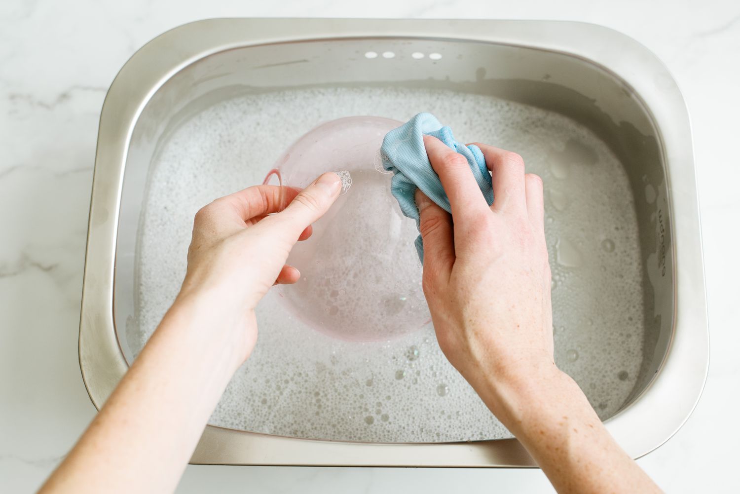 Abat-jour en verre lavé à la main avec un chiffon en microfibre, un seau d'eau et du liquide vaisselle