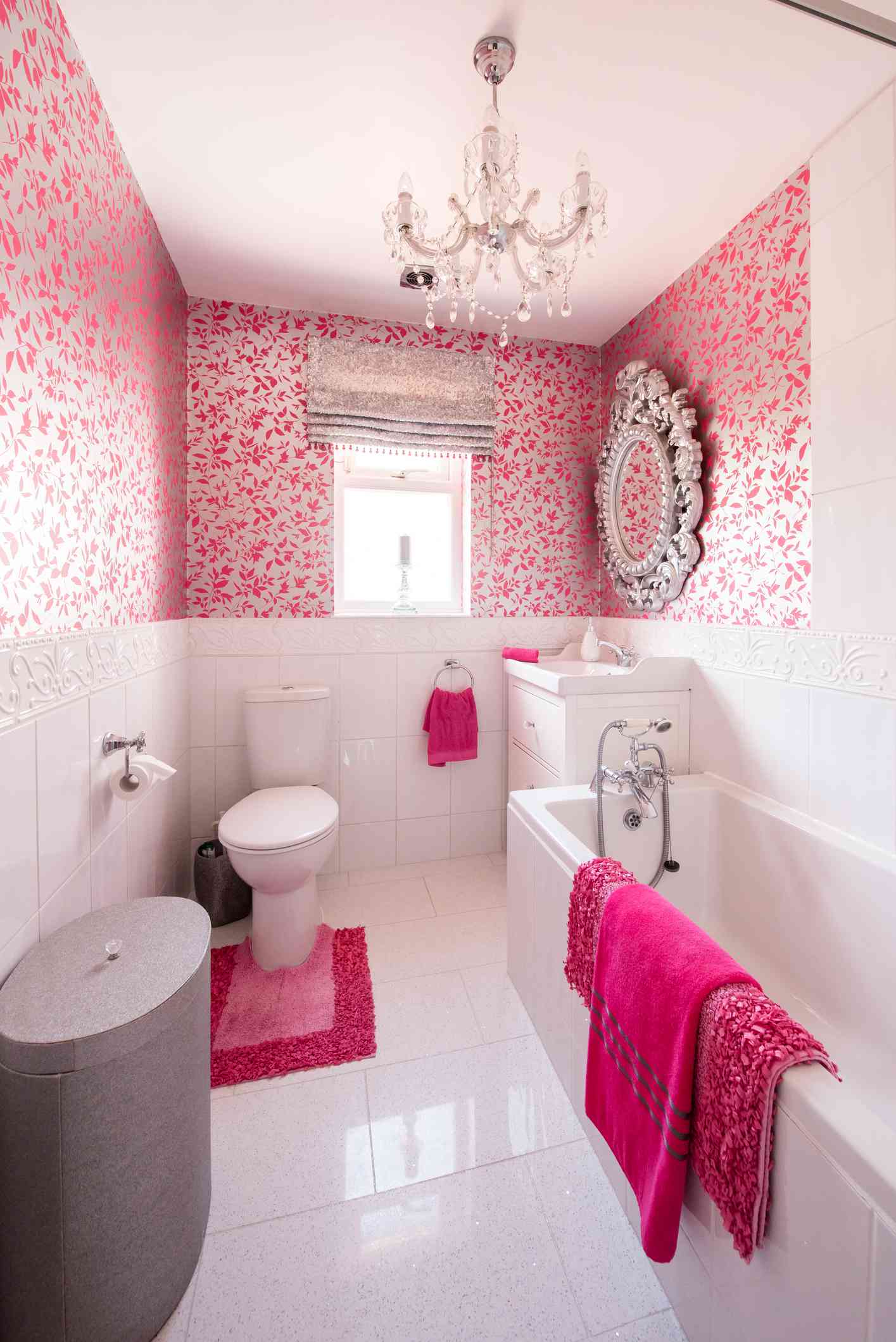 Baño rosa con lámpara de araña y espejo ornamentado