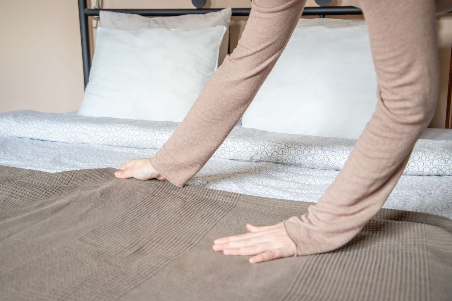 Brown blanket being adjusted on bed