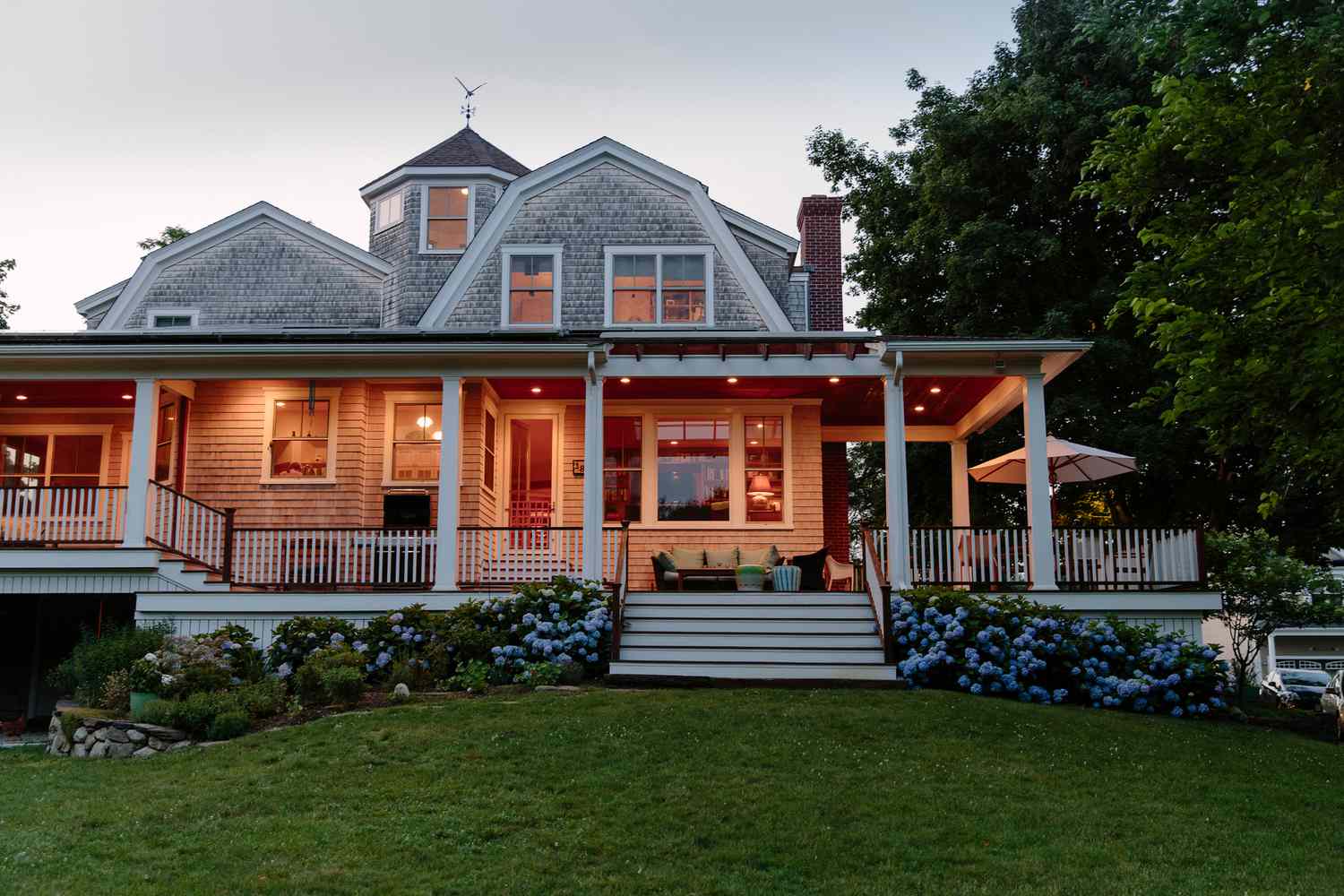 Craftsman home with wraparound porch at dusk