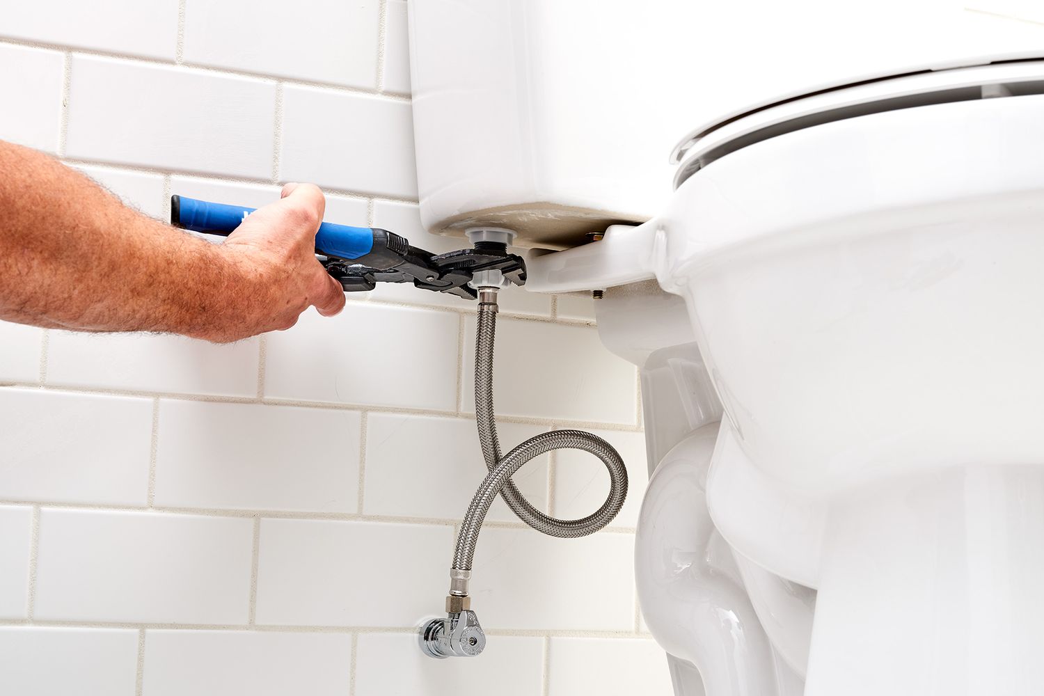 Water supply line being unscrewed from toilet with pliers