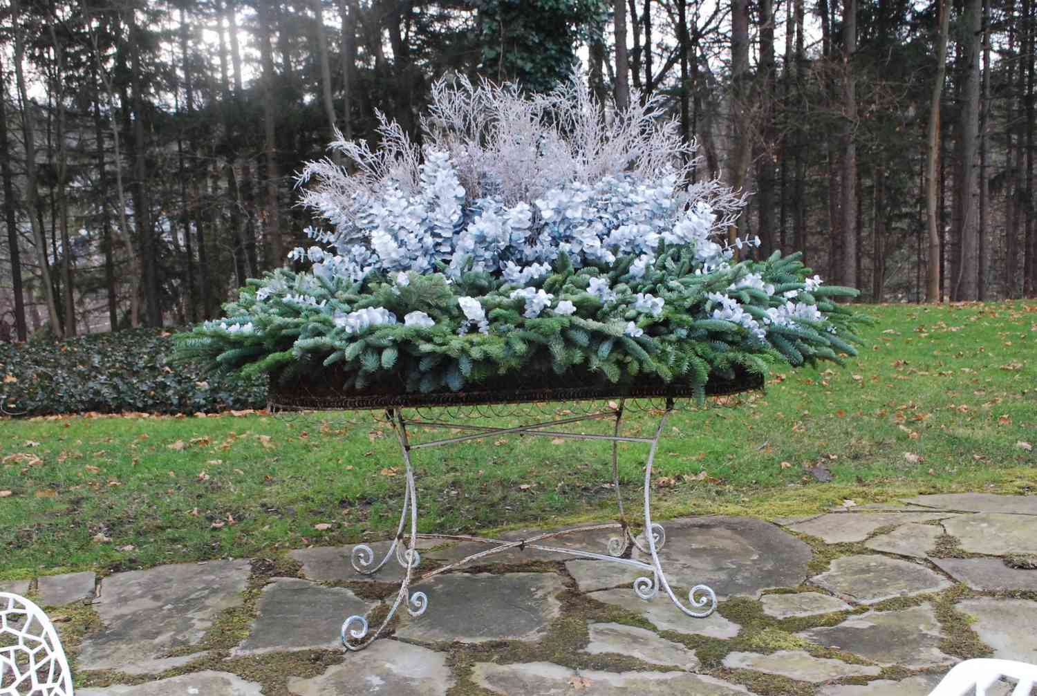 arreglo invernal en mesa exterior con ramas de hoja perenne, eucalipto y artemisia