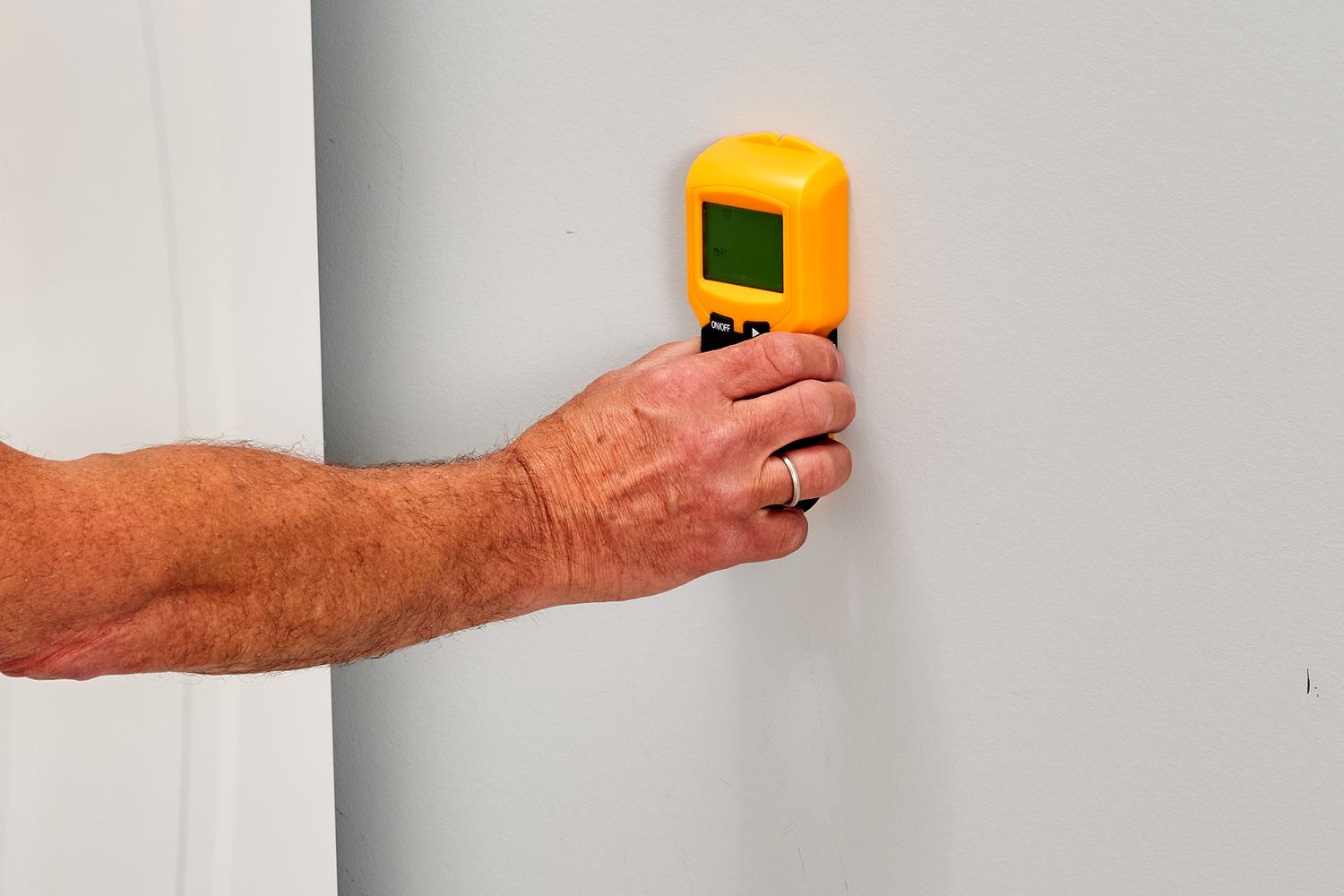 Yellow stud finder placed against wall