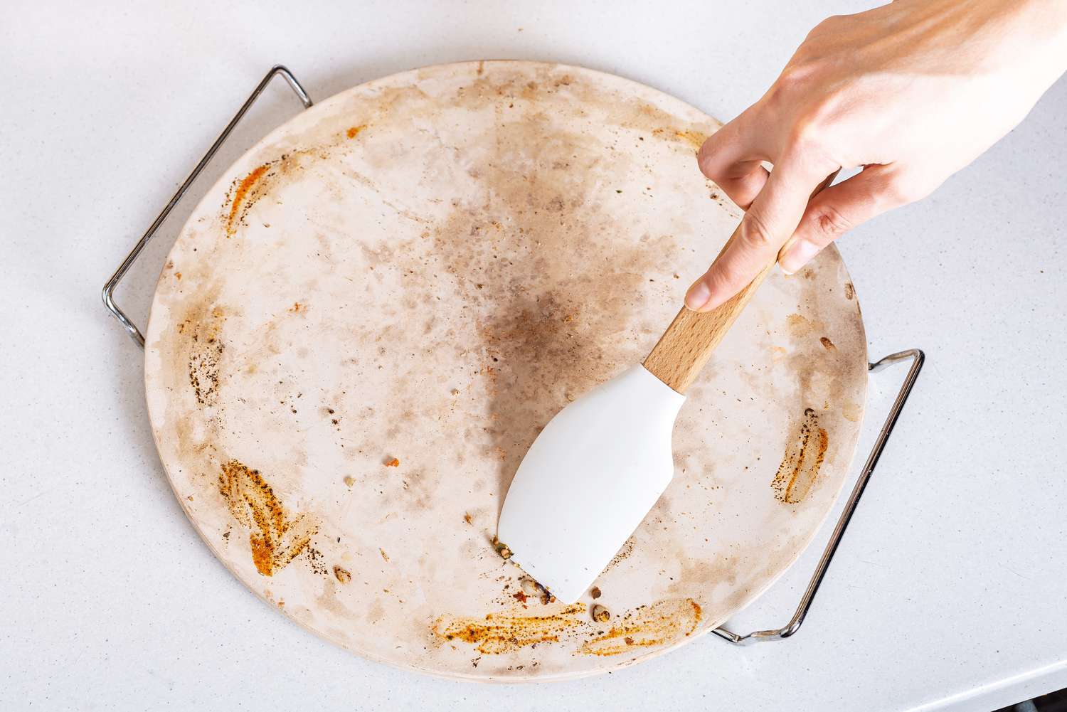 Gummispachtel schabt Pizzastücke vom Stein ab