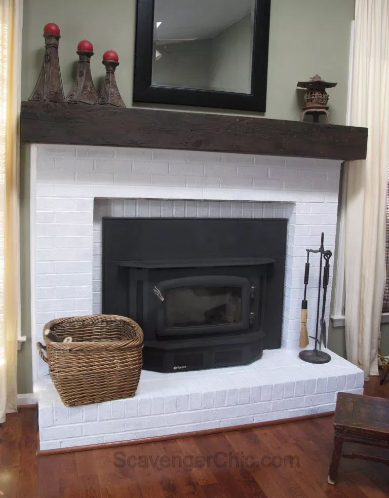 Une cheminée en briques blanches avec un manteau brun foncé