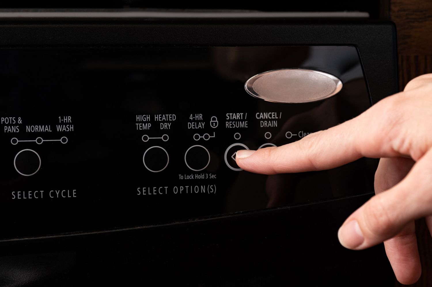 Botão da máquina de lavar louça pressionado para iniciar a lavagem da louça