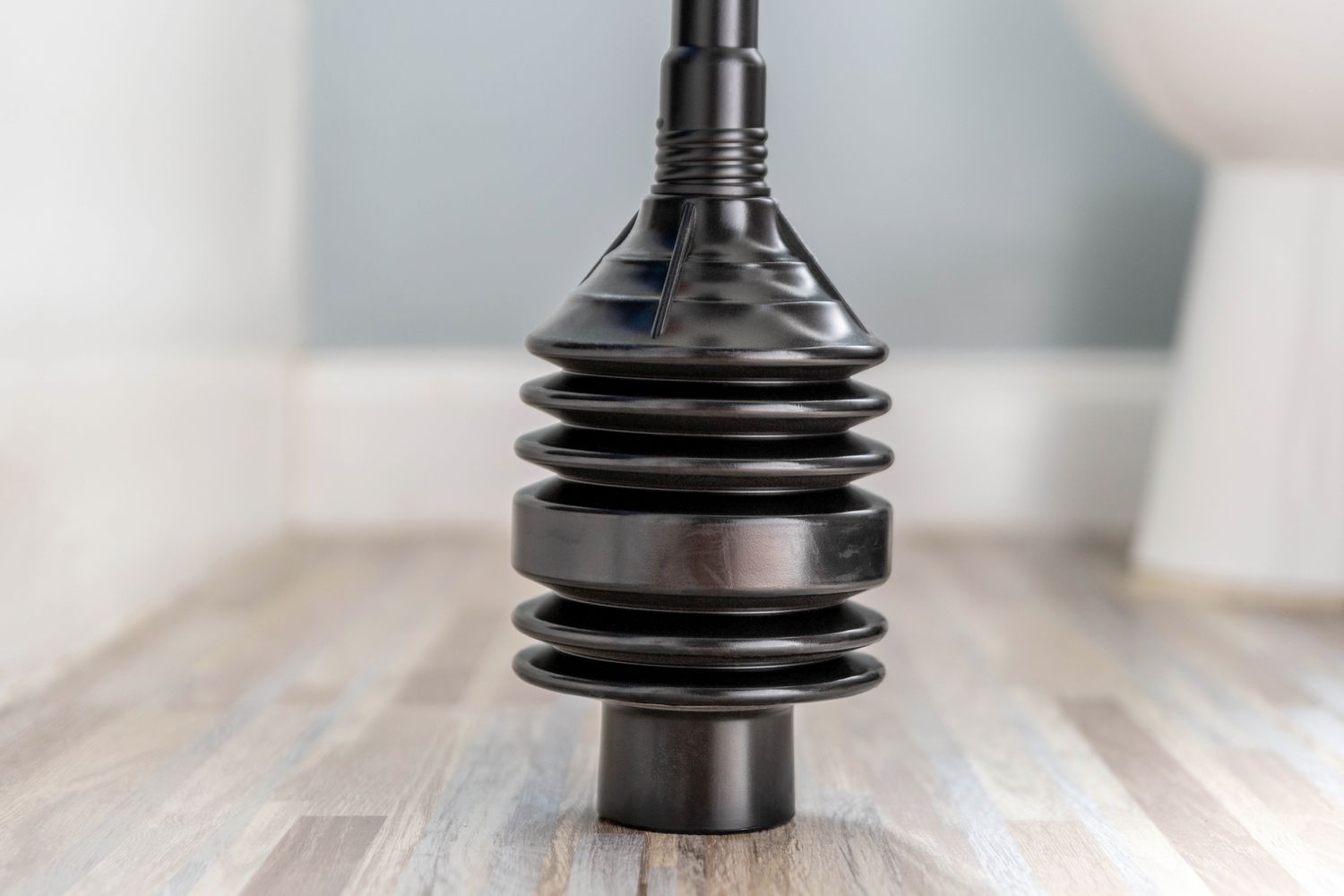 Black accordion plunger on bathroom floor